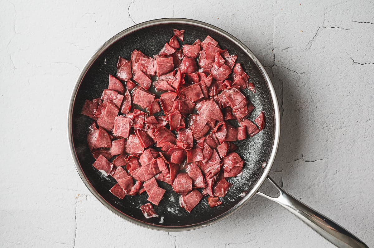 Chopped chipped beef pieces sautéing in a nonstick skillet.