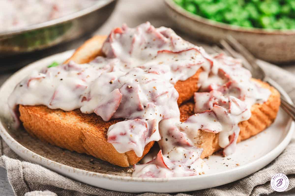 Toasted bread slices covered in creamy chipped beef gravy on a plate, ready to serve.