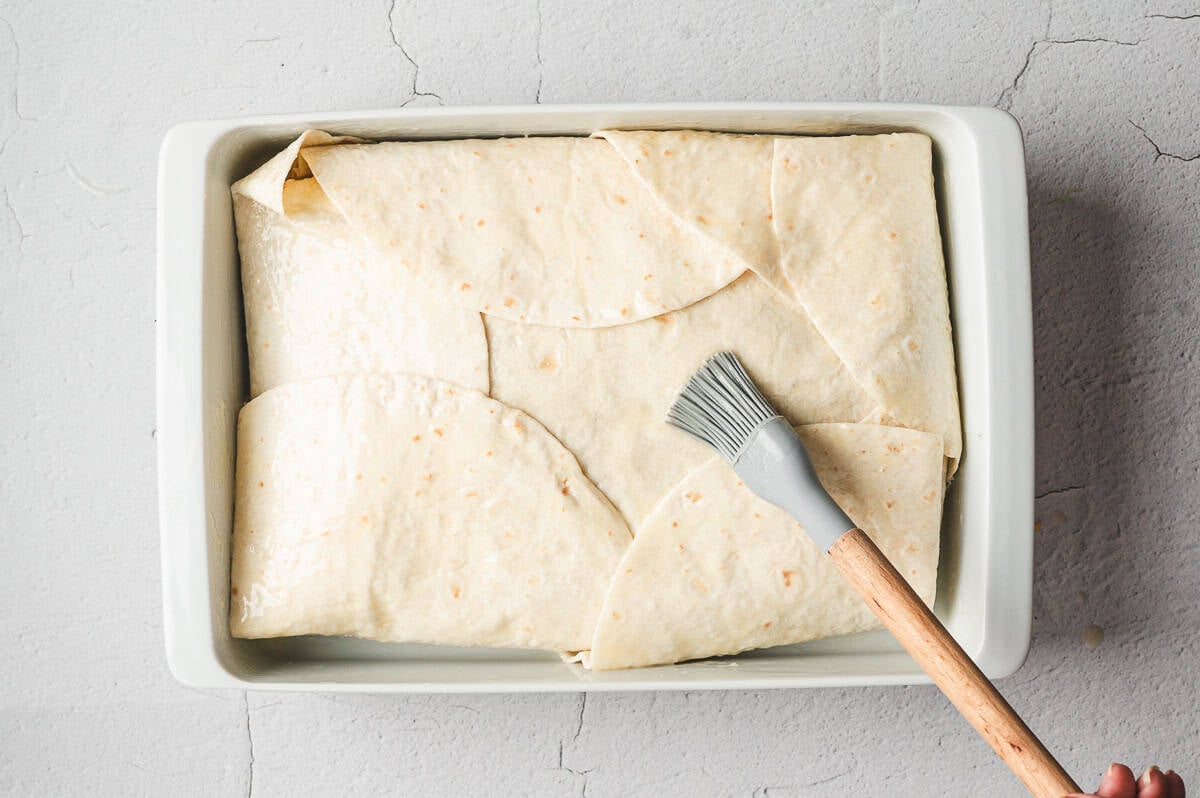 Casserole brushed with melted butter on top of folded tortillas before baking.