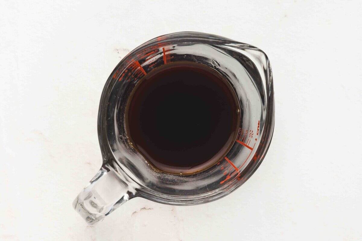 Small measuring cup filled with dark soy sauce, mirin, and sugar mixture for the glaze