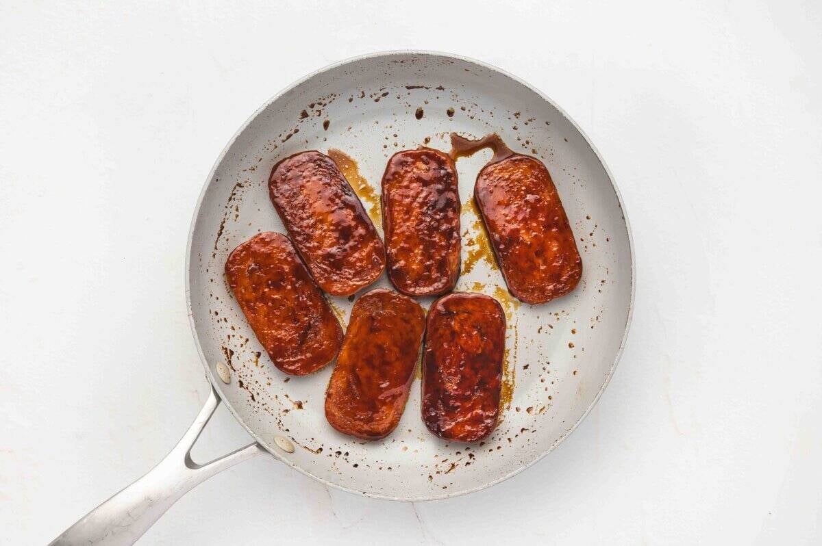 Pan with Spam slices coated in thick, caramelized soy glaze