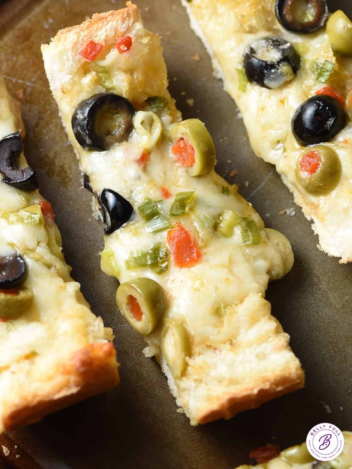 overhead slice of gooey Olive Cheese Bread on baking sheet