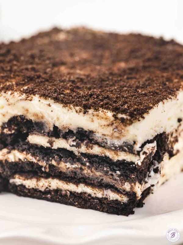 A close-up slice of Oreo tiramisu showing distinct layers of coffee-soaked Oreos and fluffy mascarpone cream, topped with crushed Oreo crumbs.