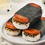 Plate of Spam Musubi stacked three high, wrapped in nori with rice and furikake seasoning visible