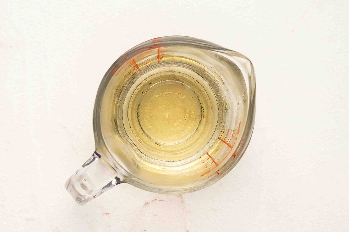 Clear glass measuring cup with rice vinegar, sugar, and salt mixture for seasoning sushi rice.