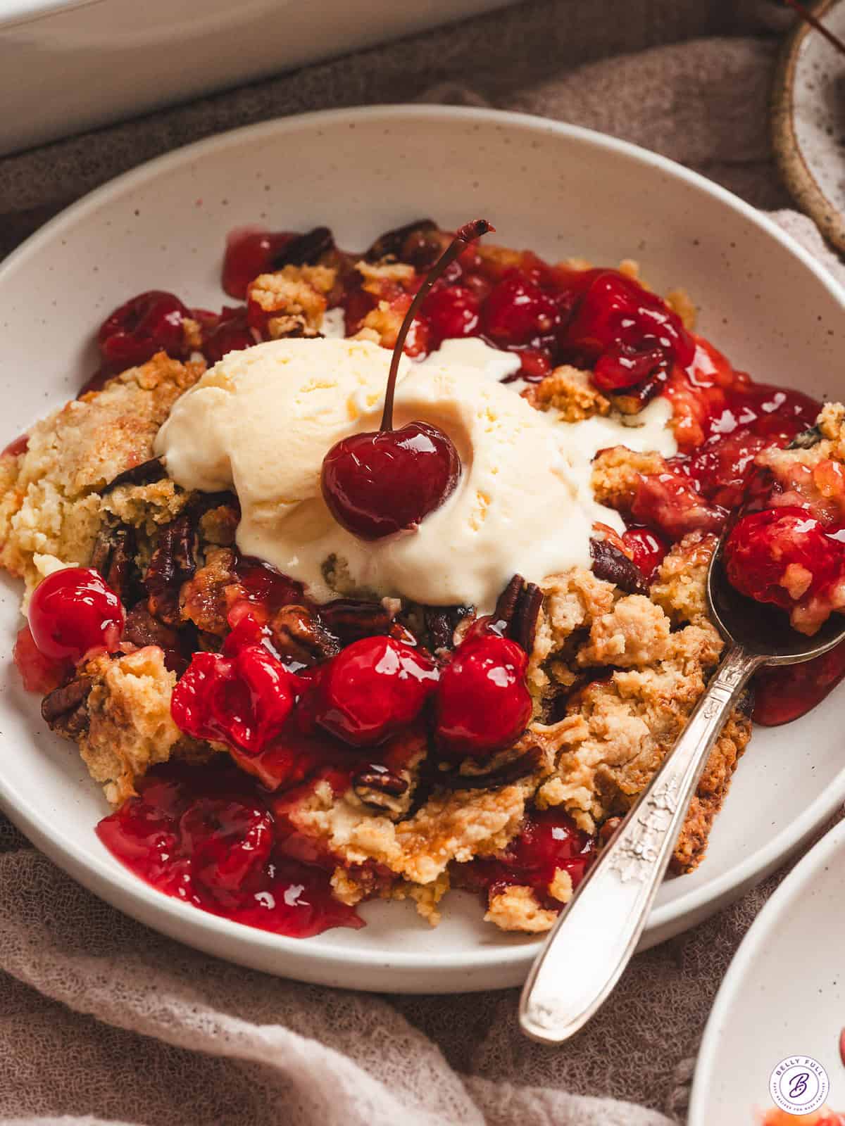 Cherry Dump Cake in bowl with vanilla ice cream