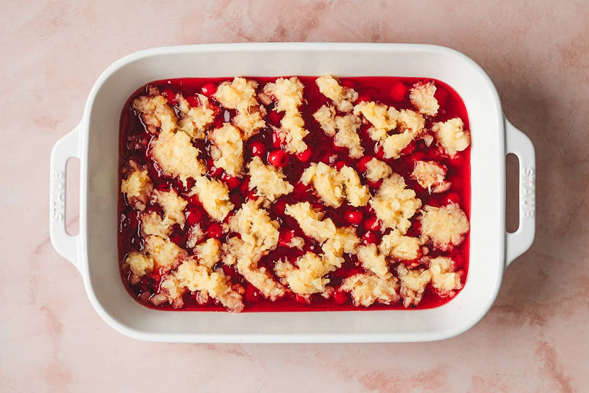 cherry pie filling topped with crushed pineapple in casserole dish