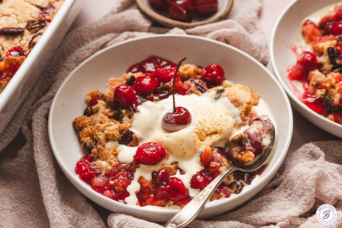 Cherry Dump Cake in bowl with vanilla ice cream