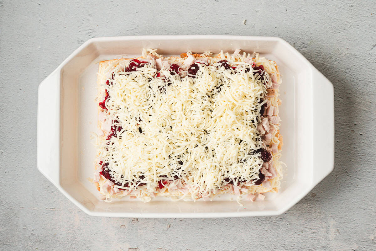 Cranberry layer covered with the remaining shredded Monterey Jack cheese in a baking dish.