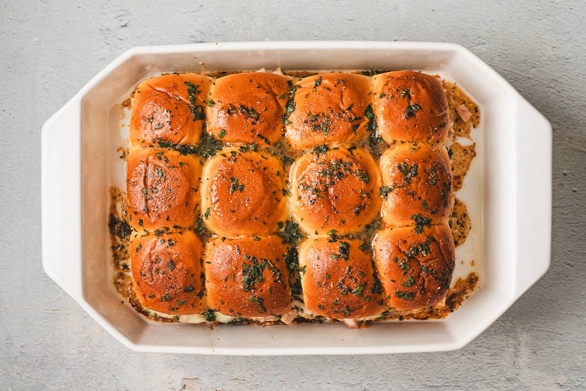 Cranberry turkey sliders freshly baked in a white dish with golden tops and melted butter glaze.