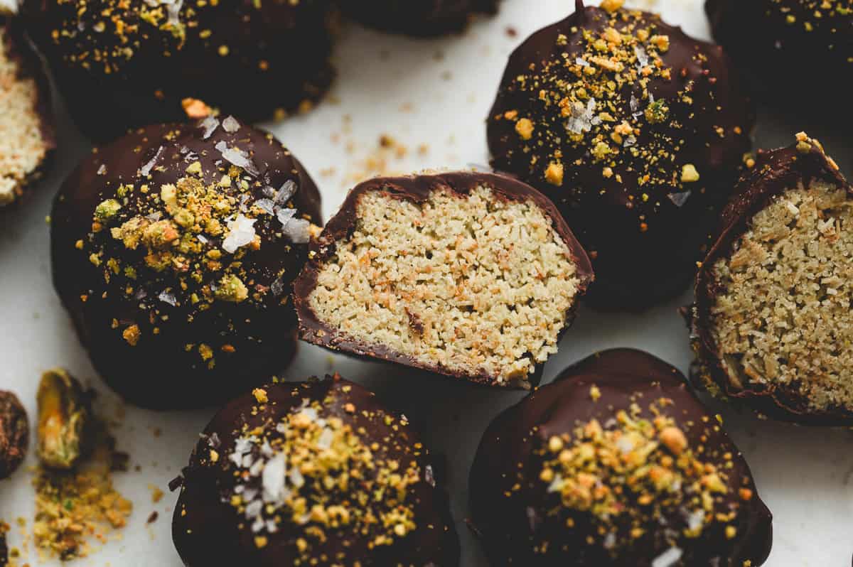 Close-up of Dubai chocolate truffles showing the crisp kataifi pistachio filling inside and dark chocolate coating topped with flaky sea salt and pistachio crumbs.