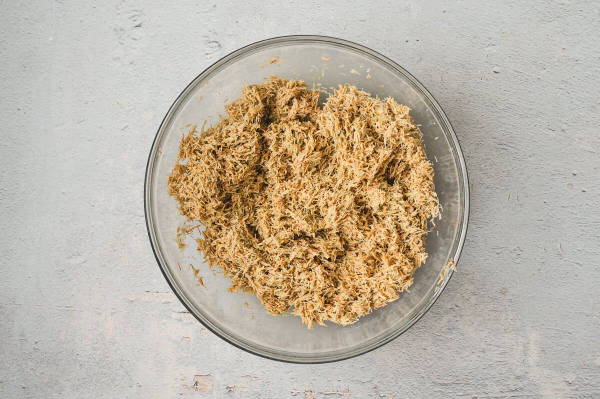 Toasted kataifi mixed with pistachio butter and tahini in a clear glass bowl, forming the base mixture for Dubai chocolate truffles.