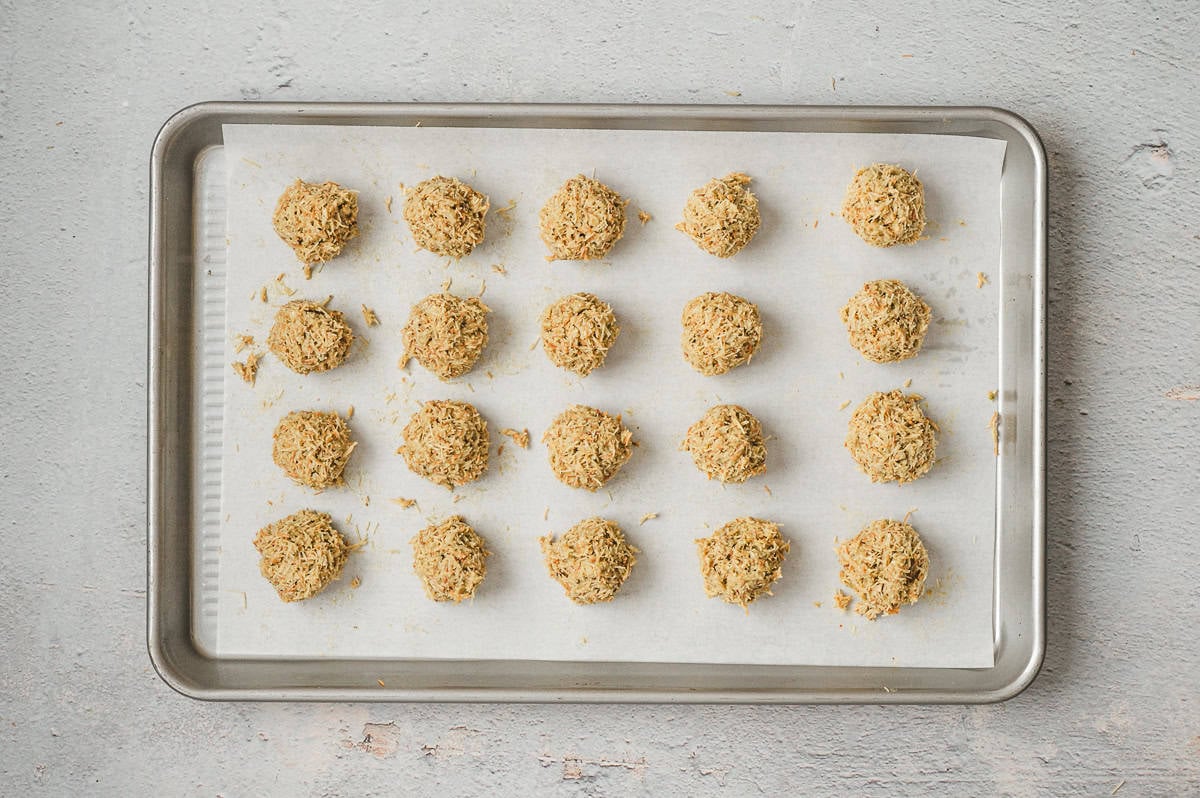Rows of kataifi pistachio truffle balls arranged on a parchment-lined baking sheet, ready to be chilled before coating in chocolate.