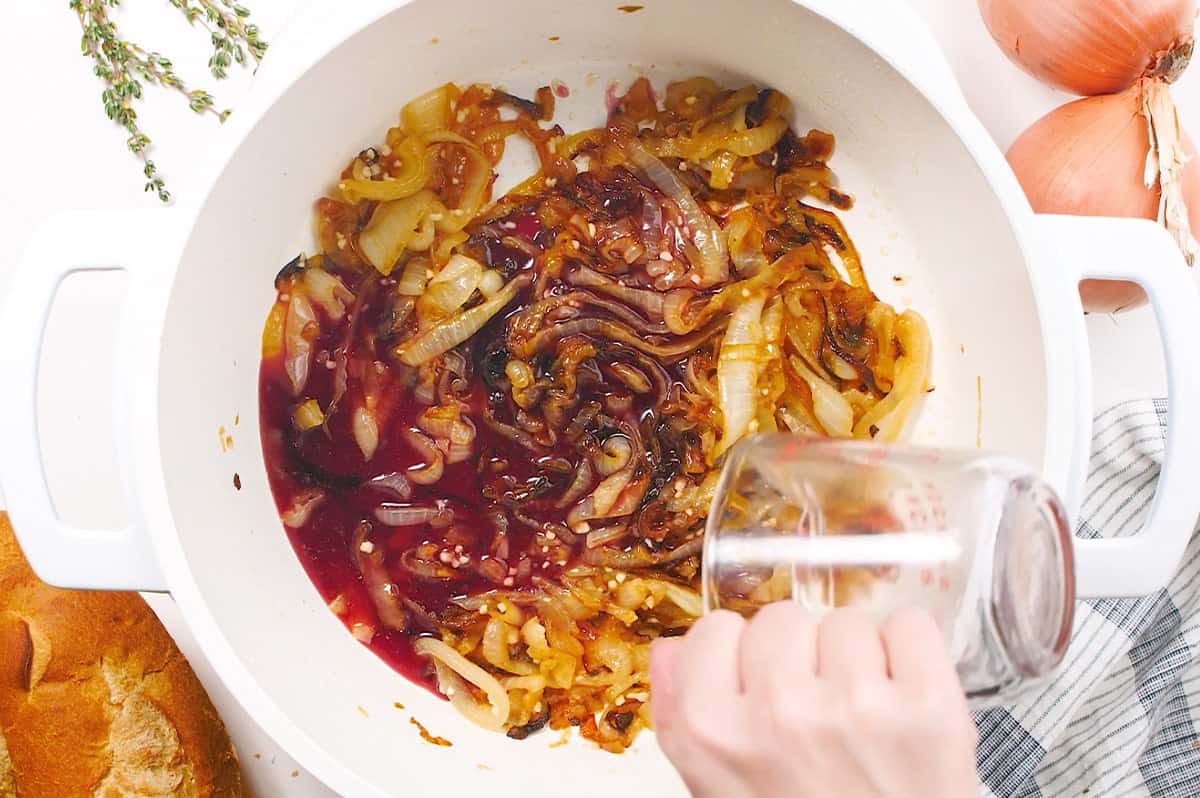 red wine being added to caramelized onions