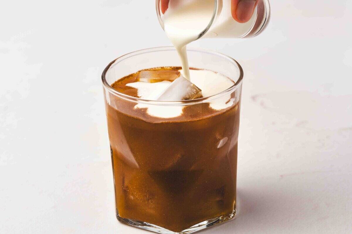 Pouring heavy cream into the glass of pumpkin and coffee mixture to create a creamy swirl in the pumpkin pie White Russian.