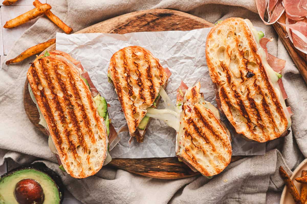 Grilled prosciutto-wrapped turkey panini slices arranged on parchment paper with visible melted cheese.