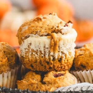 A close up of a pumpkin cream cheese muffin with a creamy cheesecake center showing through the middle.