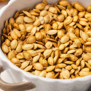 Bowl filled with golden roasted pumpkin seeds, lightly salted and ready for snacking