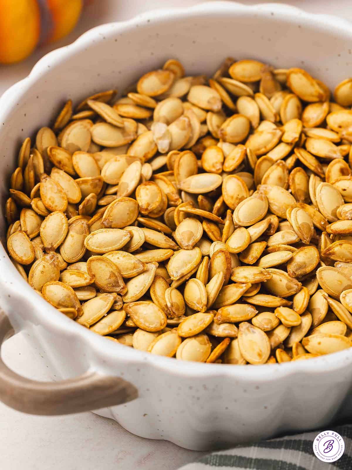 Bowl filled with golden roasted pumpkin seeds, lightly salted and ready for snacking