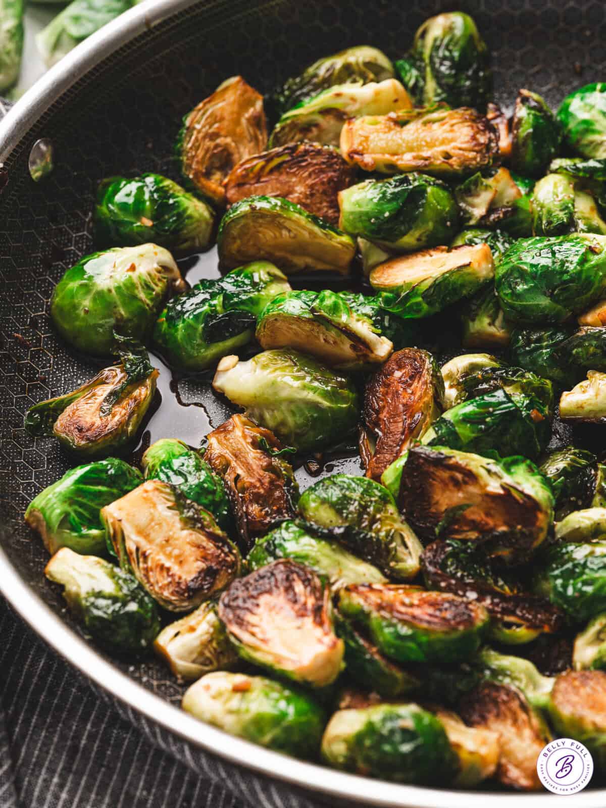 Close-up of sautéed Brussels sprouts in a skillet, golden brown on the cut sides and coated in a glossy molasses glaze.