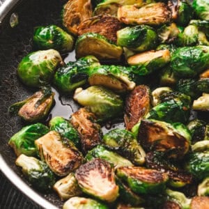 Close-up of sautéed Brussels sprouts in a skillet, golden brown on the cut sides and coated in a glossy molasses glaze.