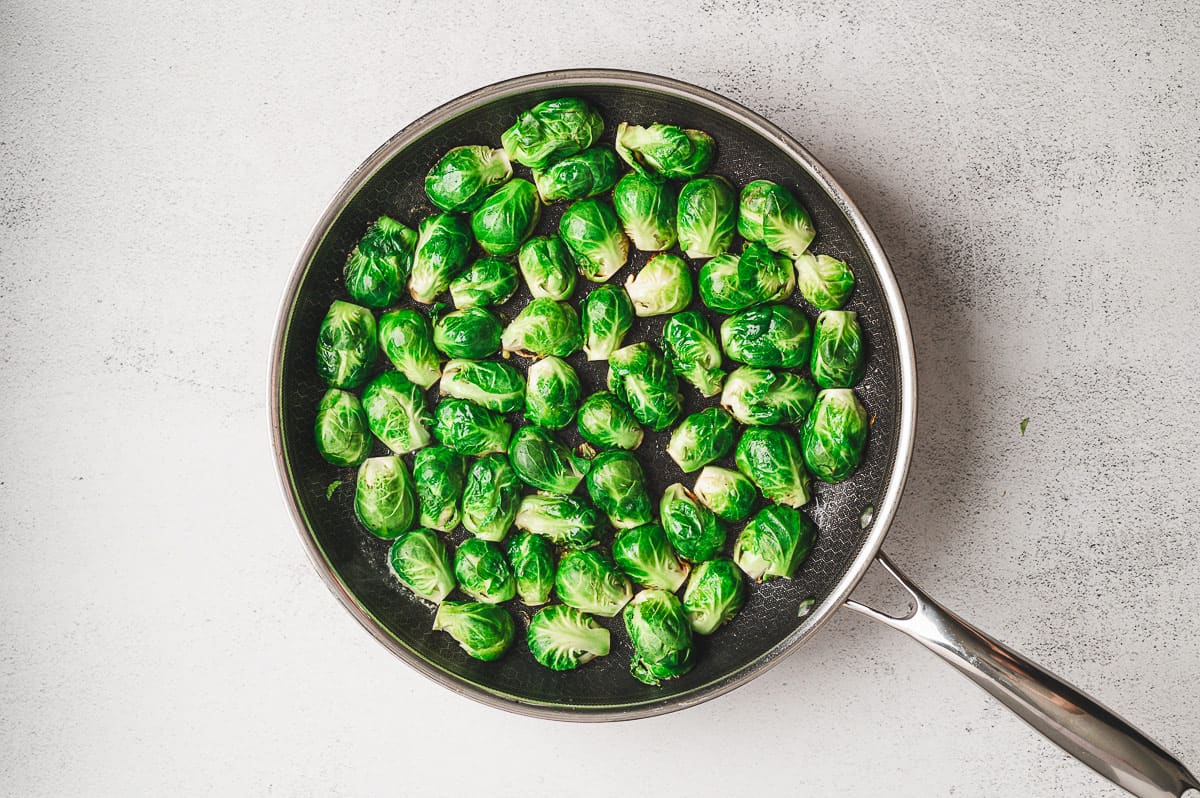 Raw halved Brussels sprouts arranged cut side down in a large skillet, ready to be seared.