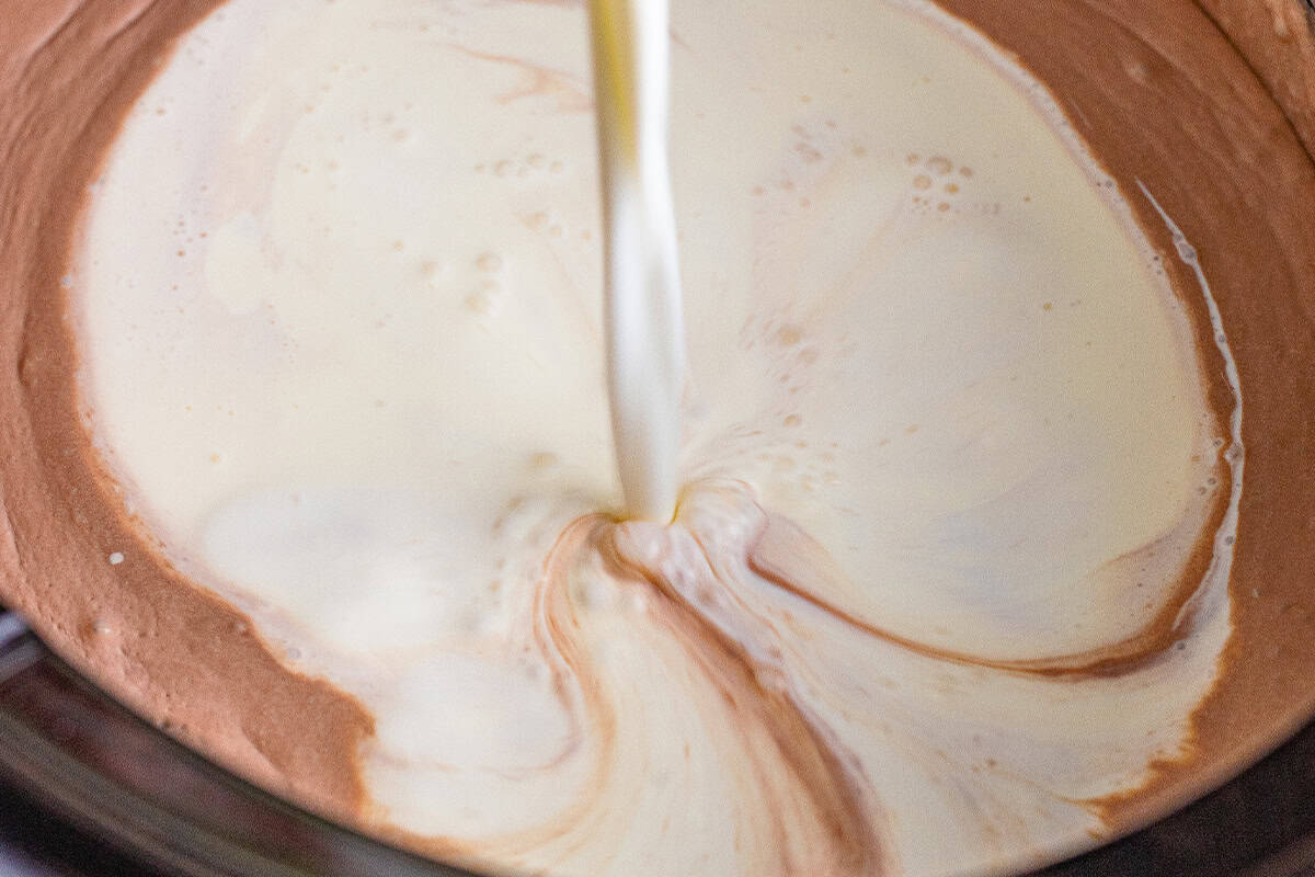 milk and cream being added to chocolate in crockpot