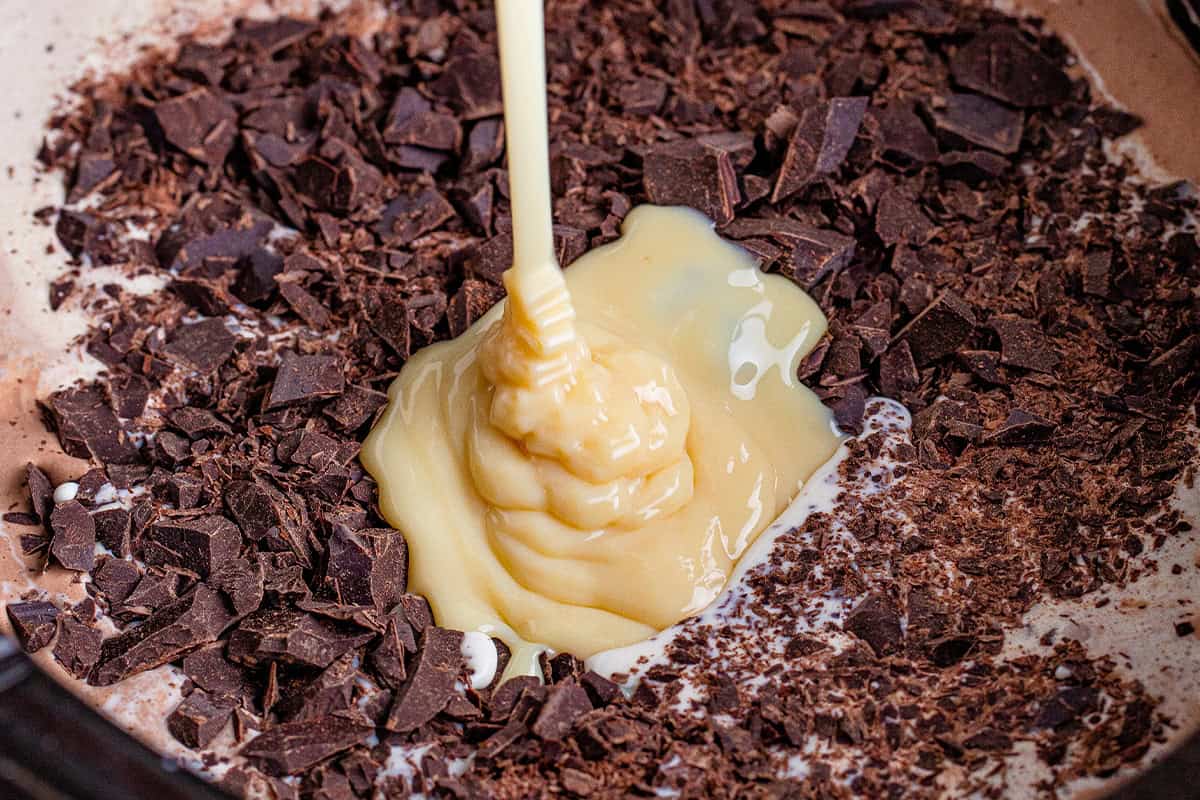 sweetened condensed milk being added to milk, cream, and chopped chocolate