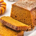 Sliced snickerdoodle pumpkin bread on a white platter, showing its soft texture and cinnamon sugar crust.