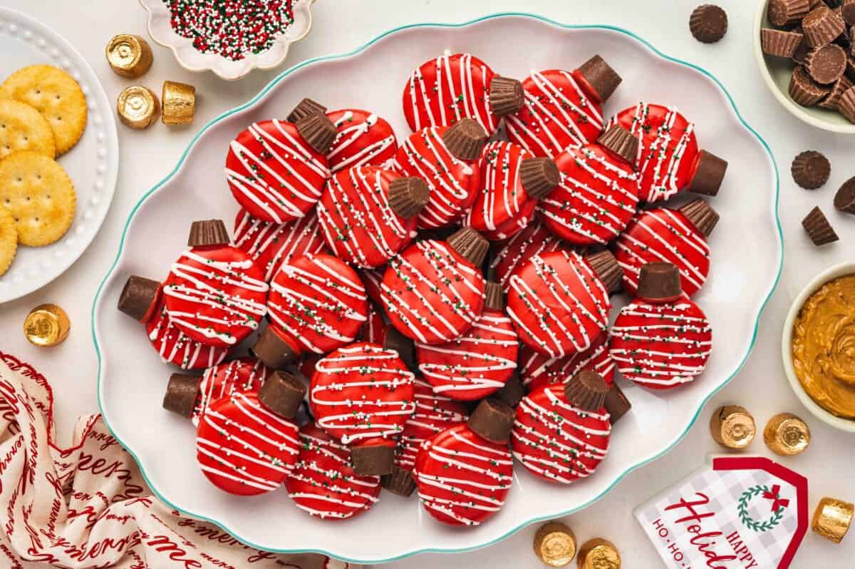 Large platter filled with red chocolate-covered Ritz cracker ornament cookies topped with Rolos and holiday sprinkles.