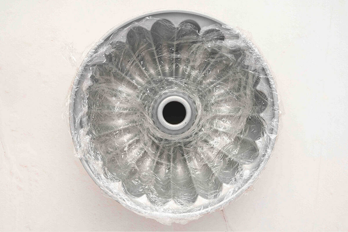 Bundt pan fully lined with plastic wrap, ready to be filled with cheese mixture.