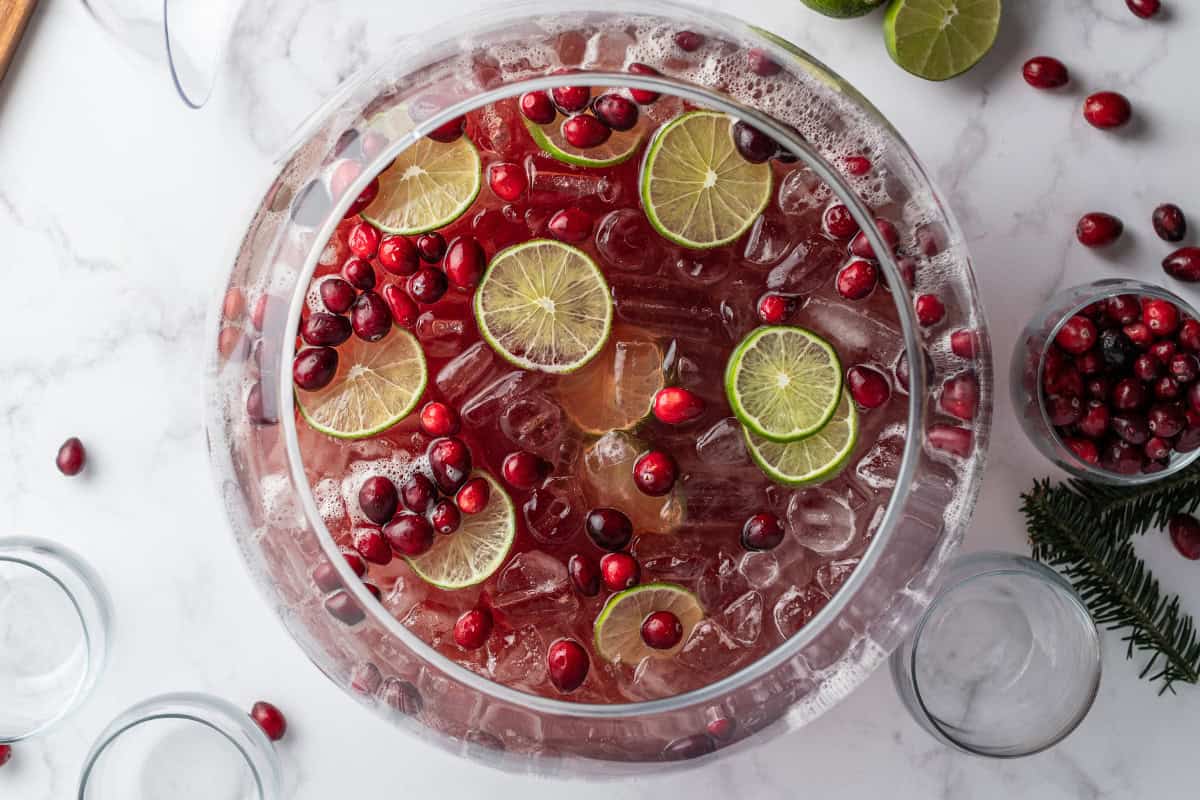 overhead holiday punch in punch bowl garnished with cranberries and lime slices