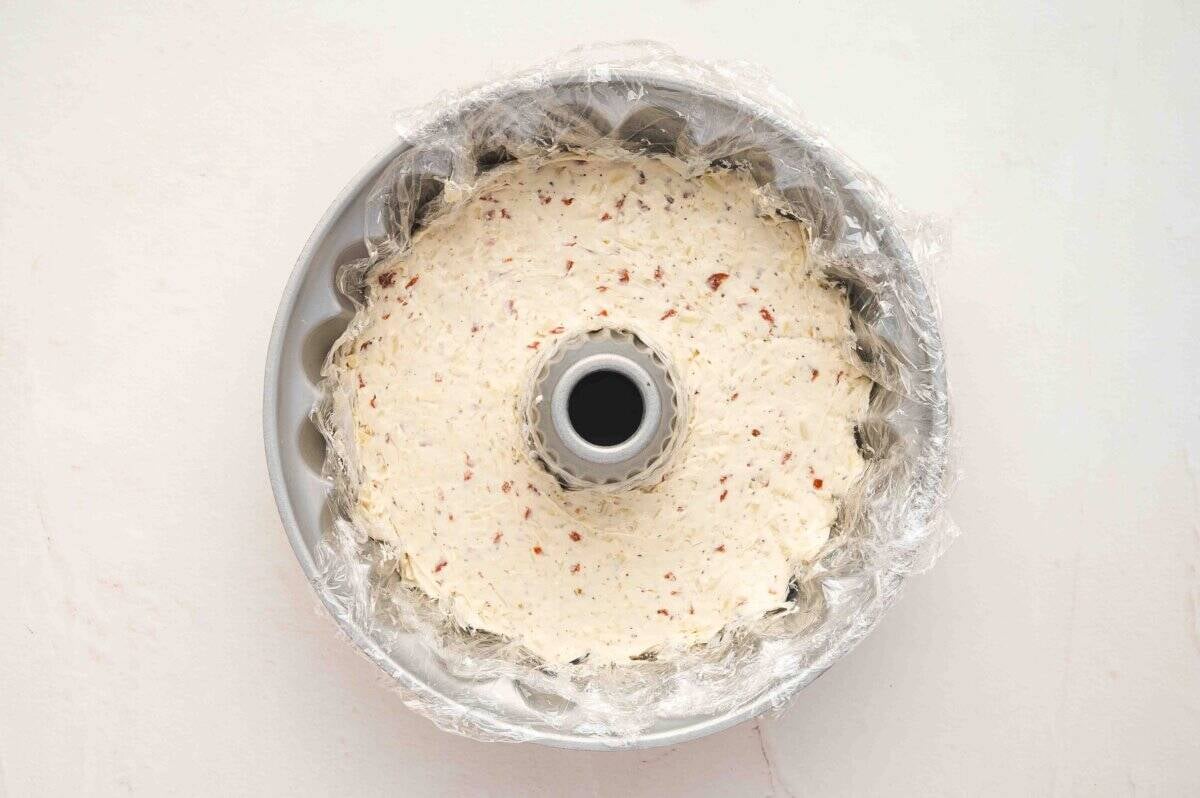 Cheese ball mixture pressed evenly into a plastic wrap-lined Bundt pan.