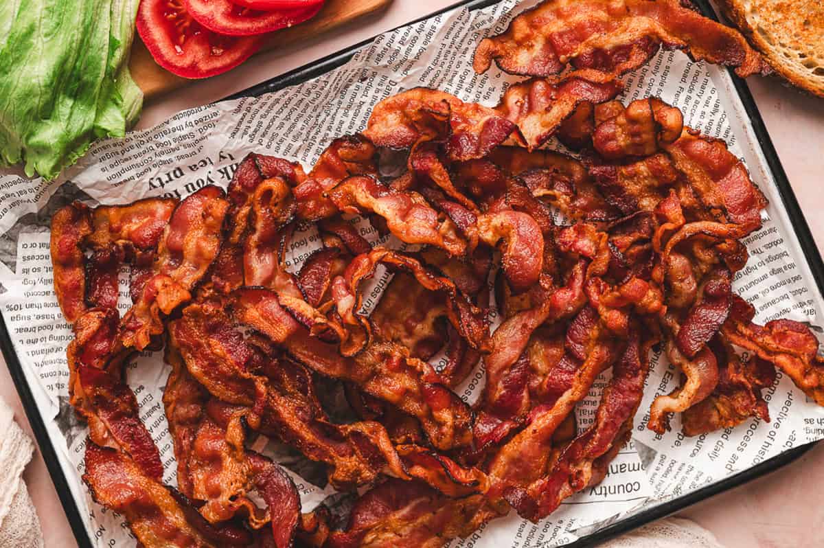 Crispy cooked bacon strips cooling on a parchment-lined baking sheet