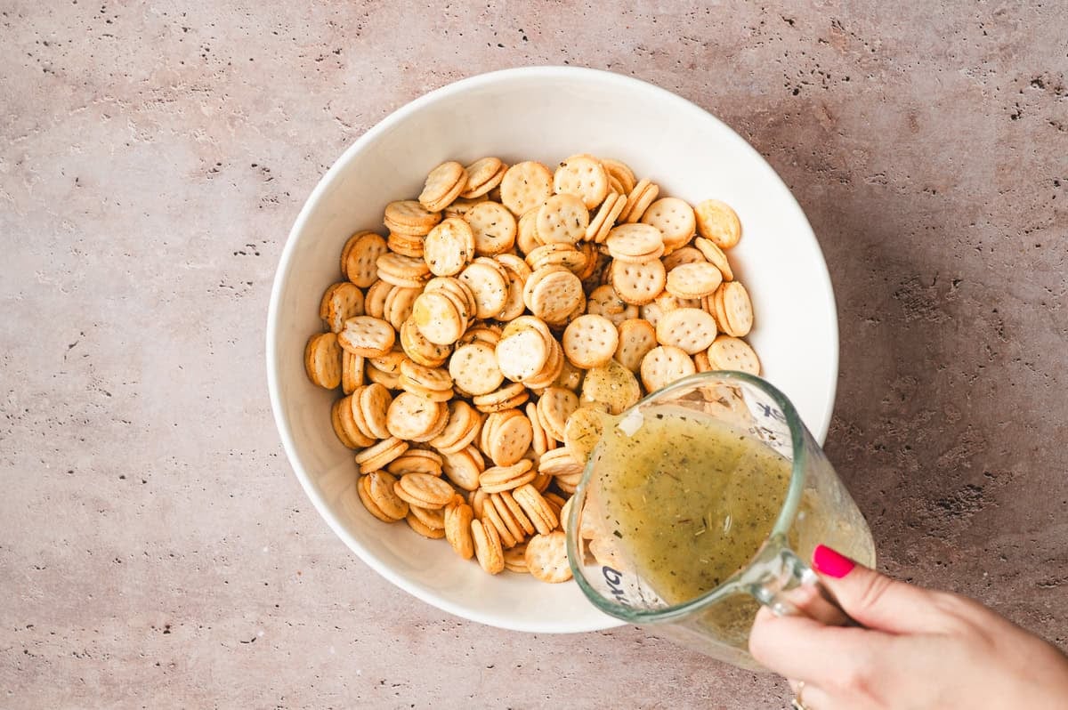 Bowl of Ritz Bits crackers with seasoned melted butter being poured over the top
