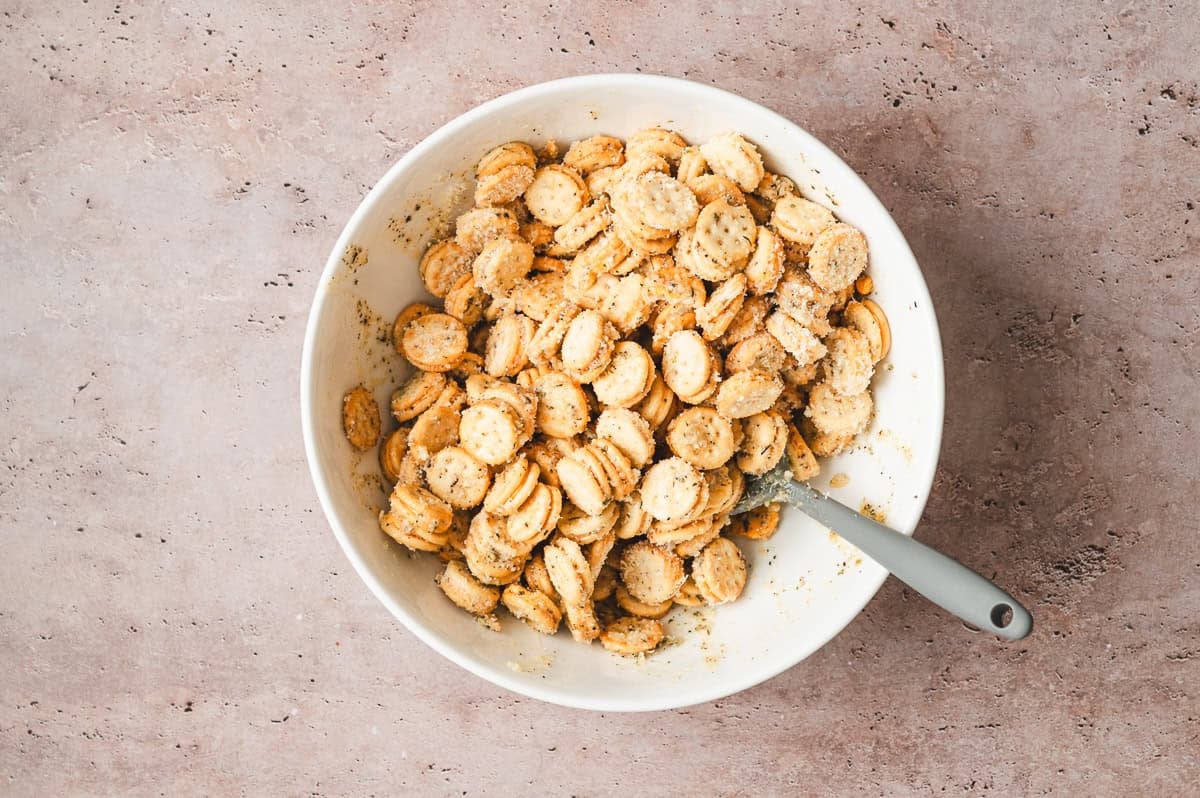 Ritz Bits crackers tossed in seasoned butter and Parmesan inside a large white mixing bowl
