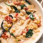 Creamy Marry Me Chicken Soup in a speckled bowl with ditalini pasta, shredded chicken, spinach, and sun dried tomatoes, served with bread on the side.