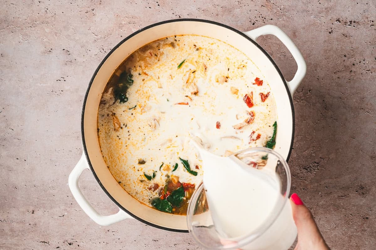 Heavy cream being poured into the soup to make it creamy and rich.
