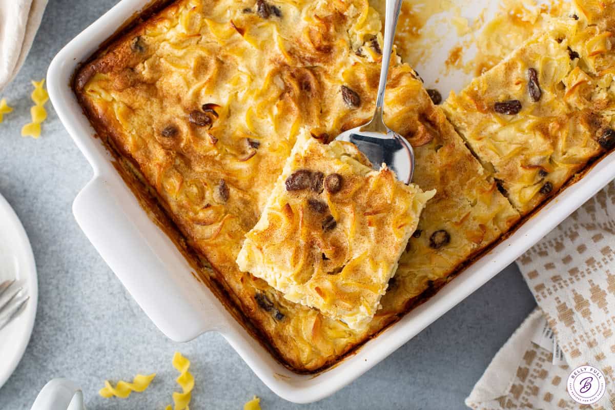 square piece of noodle kugel on serving spatula over cut casserole