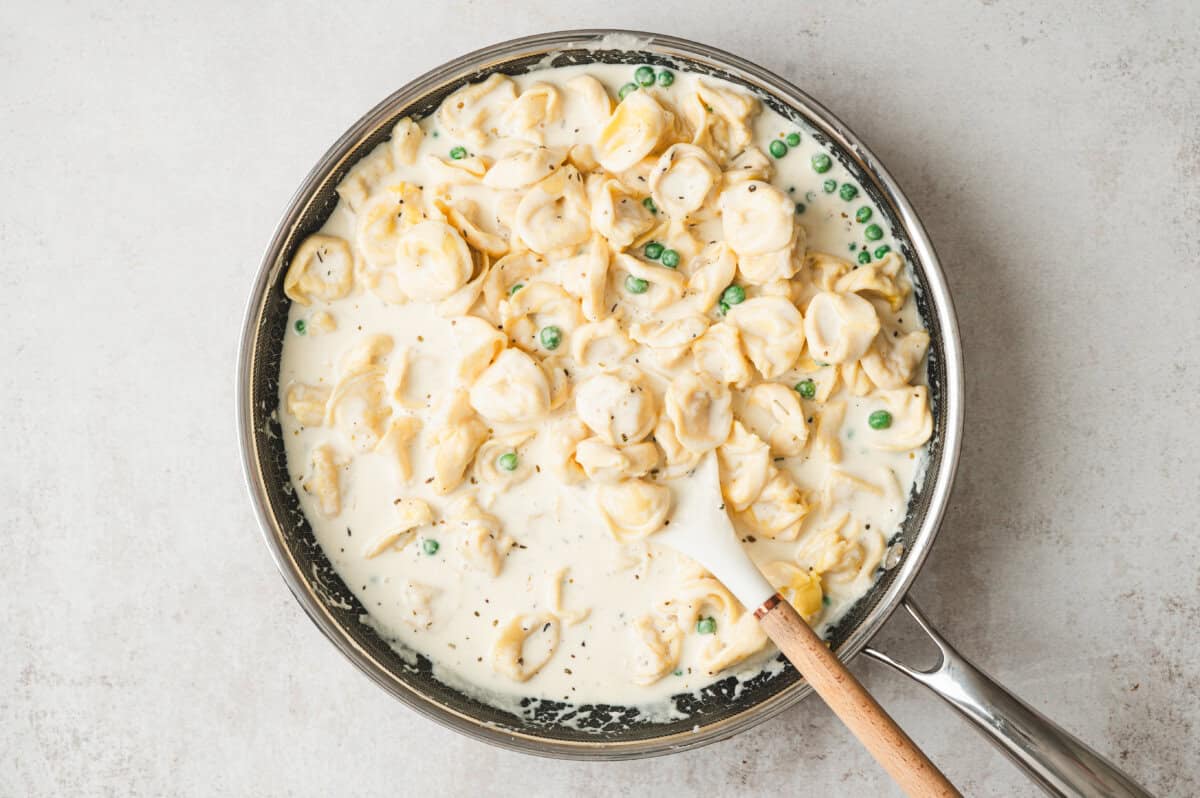 Cheese tortellini and peas tossed into creamy alfredo sauce in a large skillet with peas.