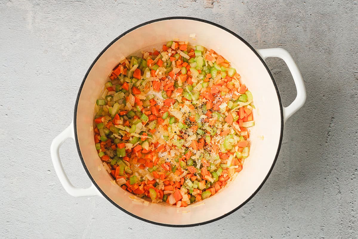 Diced onion, celery, and carrots sautéing in olive oil in a large pot until softened and translucent.