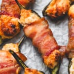 close up roasted Bacon Wrapped Jalapeno Poppers on parchment paper
