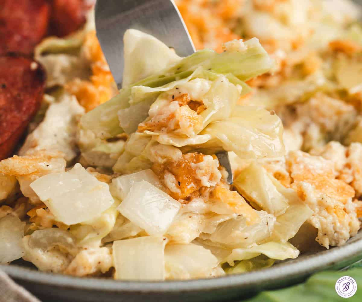 A fork taking some cabbage casserole off a plate.