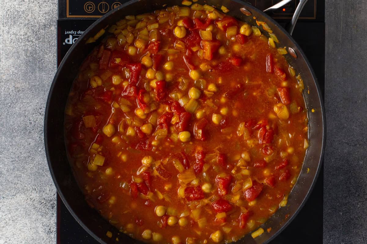 tomato broth, seasonings, and chick peas simmering on skillet