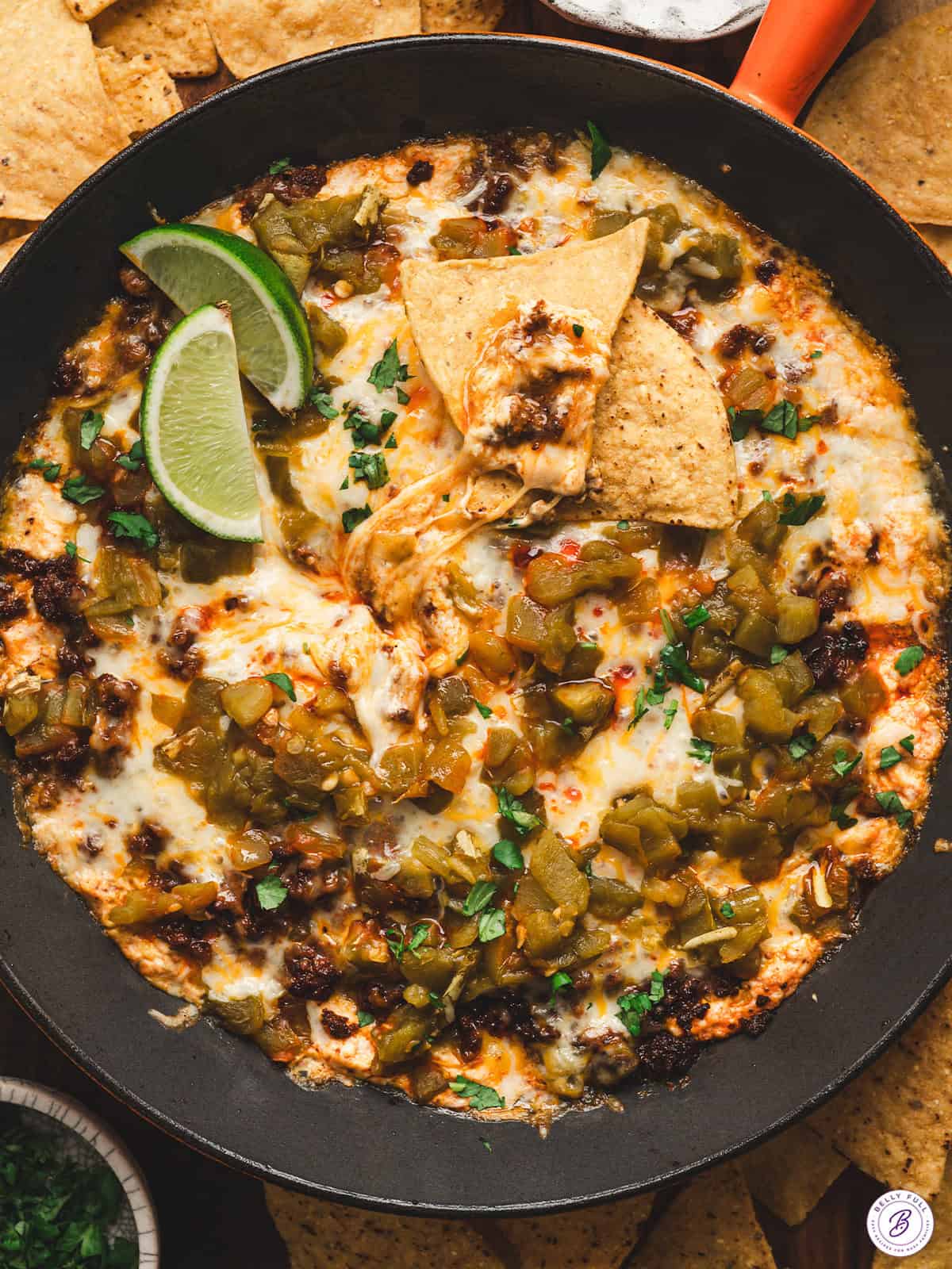 Baked chile relleno dip with melted cheese, roasted green chiles, and chorizo served in a cast iron skillet with tortilla chips and lime wedges.