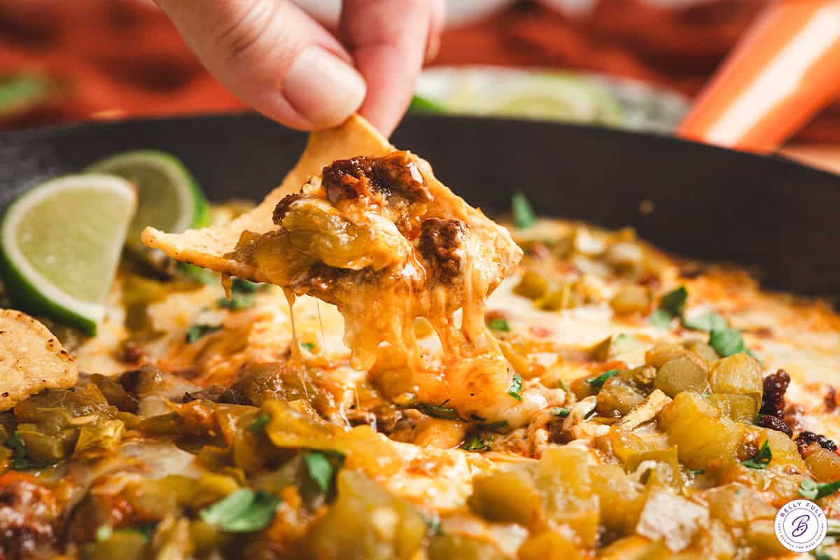 fingers dipping a chip into chile relleno dip