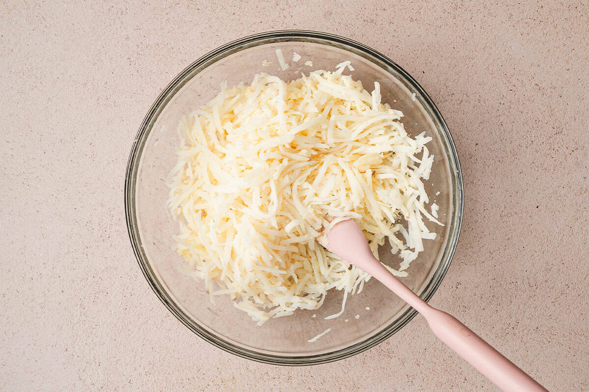hash browns being mixed with butter in bowl