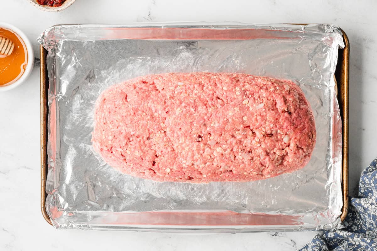 loaf of uncooked meatloaf on baking sheet