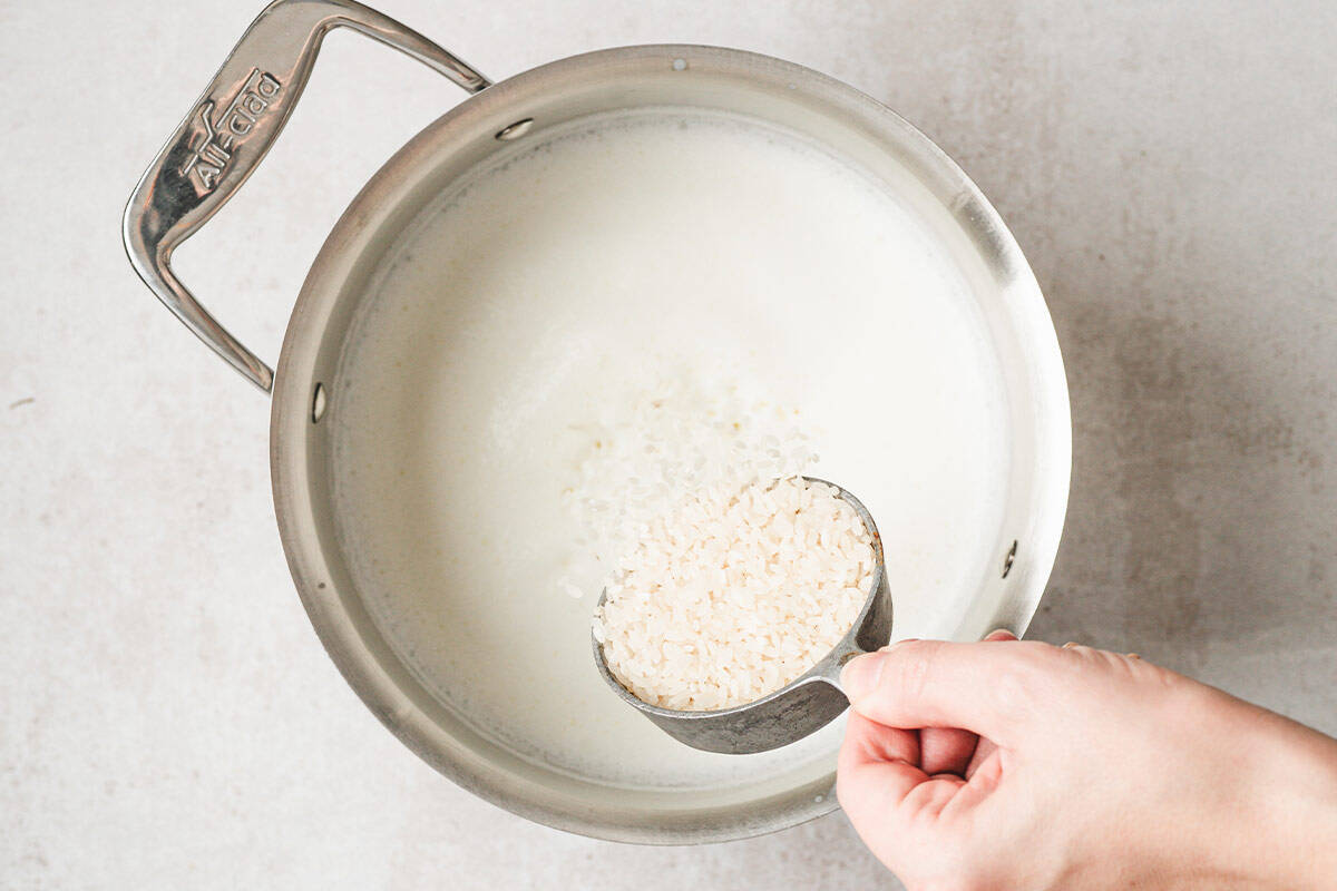 medium grain rice being poured into pot with milk