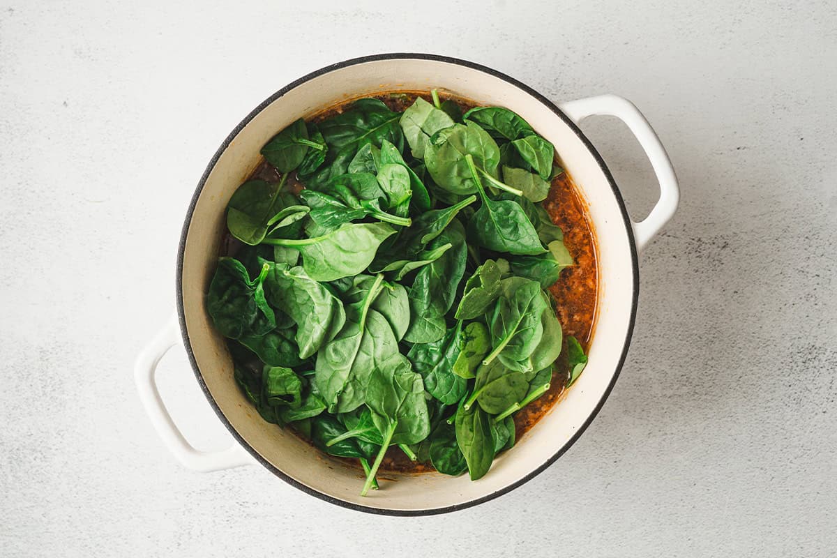 fresh baby spinach added to soup pot